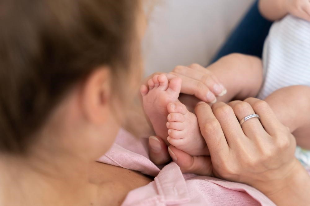 Mamãe segurando pezinhos do bebê e tendo os primeiros cuidados no pós-parto